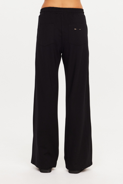 Rear shot from the waist down showing back patch pockets and a small embroidered contrast arrow logo on the right pocket of The Upside Roma Pant in black.
