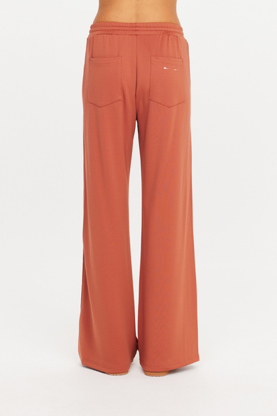 Rear shot from the waist down of The Upside Roma Pant in Desert Rose, highlighting the back patch pockets and embroidered arrow logo.