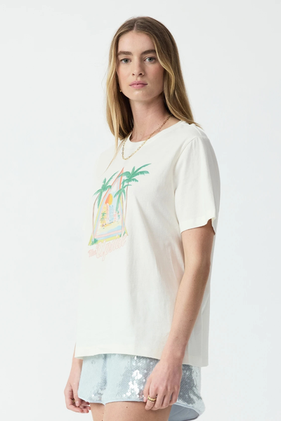 Studio three-quarter side shot of a model wearing a cream organic cotton t-shirt with a vintage-inspired tropical front chest graphic.