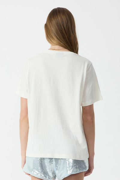 Studio rear view from the waist up of a model wearing a plain cream organic cotton crewneck t-shirt and light blue sequin shorts.