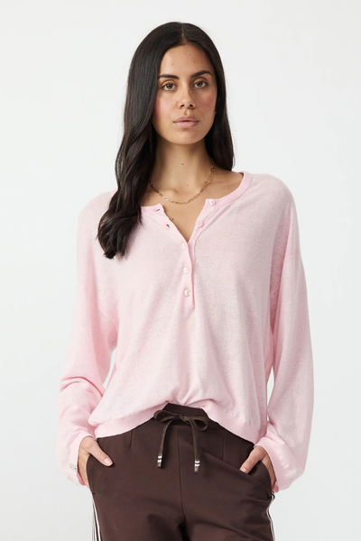 Front studio view of a model with dark hair wearing the rosewater pink linen-cotton knit button top and brown track pants.