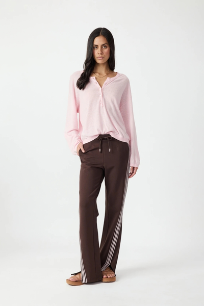 Full-length front studio view of a model wearing the pink knit button top, brown side-stripe pants, and sandals.