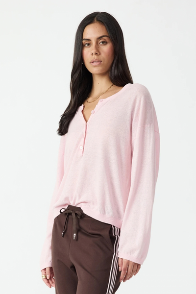 Studio three-quarter front view of a model showcasing the relaxed fit and dropped shoulders of the rosewater pink knit top.