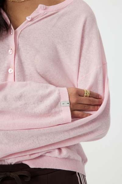 Close-up detail shot of the sleeve cuff on the rosewater knit top, highlighting the ribbed hem and branded arrow logo pip.