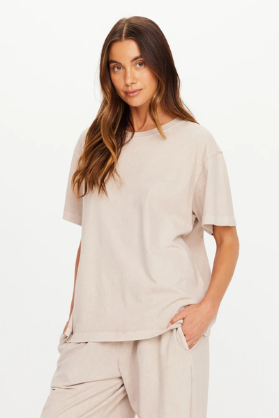 Close-up waist-up view of a model wearing the mushroom grey Sammi Tee with hand in pocket.
