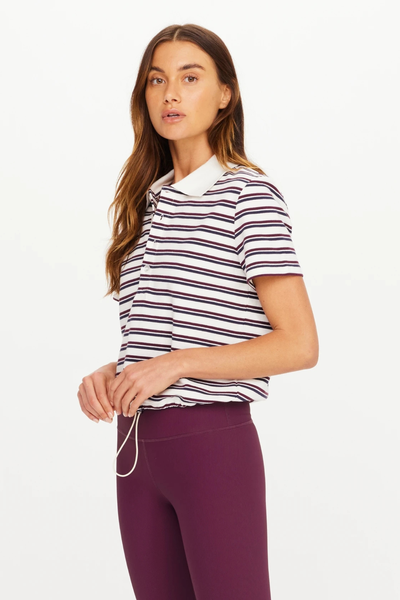 Three-quarter side view of a model wearing The Upside Sophie Cropped Polo Shirt in striped organic cotton piqué.