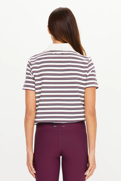 Rear view of a model wearing The Upside Sophie Cropped Polo Shirt in navy, maroon, and cream stripes, showing the short sleeve cut and cropped length.