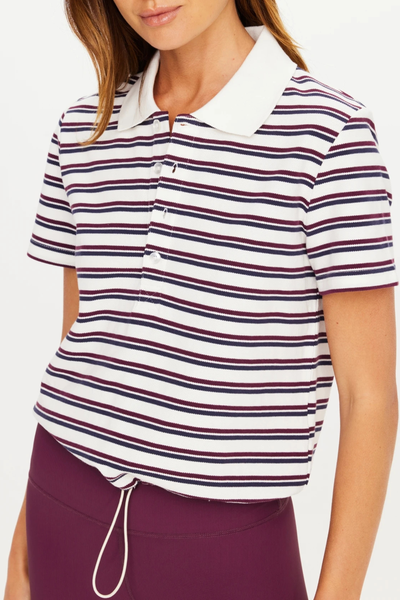 Close-up front view of The Upside Sophie Cropped Polo Shirt, detailing the cream buttons, ribbed collar, and adjustable drawcord waist with silver toggles.