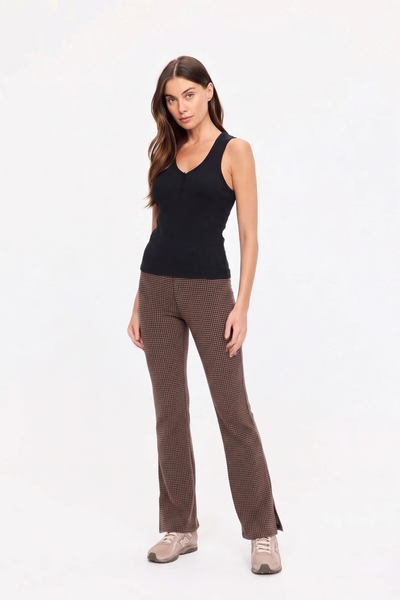 Full-length studio front view of a model standing straight, wearing the geo check flare pants paired with a black tank top and sneakers.
