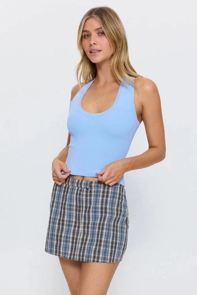 Front three-quarter angle of a model wearing the fitted Thrills Astra V Neck Tank in Placid Blue paired with a blue and grey plaid skort.
