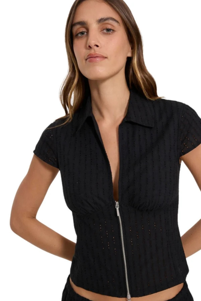 Close-up front view of model wearing the Thrills Danica Broderie Anglaise Top in Black showing the silver front zipper, textured eyelet embroidery, and open collar neck.