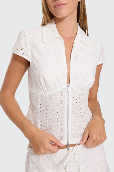 Close-up shot of the white Thrills Danica Broderie Anglaise Top showing the silver zip front, eyelet embroidery pattern, bust seam details, and collar.