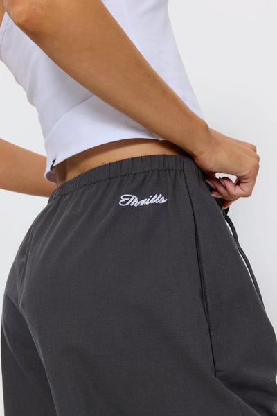 Close-up back hip detail shot of the Thrills Gridlock Ripstop Pant in Charcoal showing the elastic waistband, white script logo embroidery, and cotton ripstop texture.