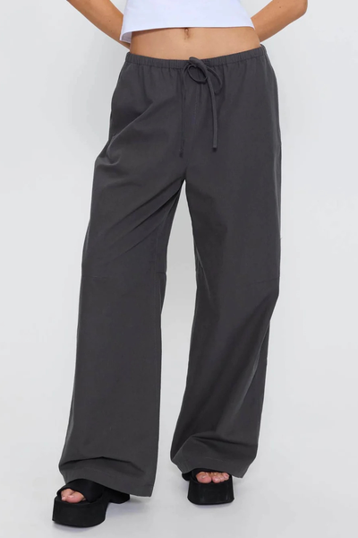 Front lower-body view of model wearing the wide straight-leg Thrills Gridlock Ripstop Pant in Charcoal paired with black platform sandals and a white crop top.