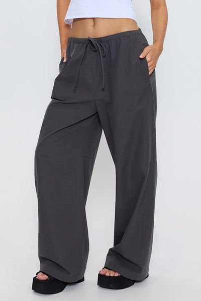 Three-quarter front view of model with hand in pocket wearing the relaxed fit Thrills Gridlock Ripstop Pant in Charcoal, featuring a drawstring elastic waist and knee seams.