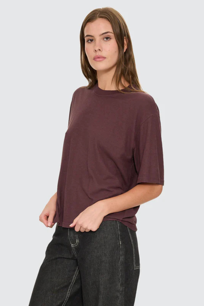A closer front e-commerce image highlighting the tee's high-hip length, styled simply with relaxed washed denim to emphasize an effortless streetwear look.
