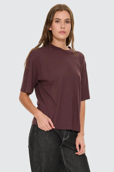 A three-quarter side angle studio shot showcasing the casual drop-shoulder seam construction and the easy, boxy drape across the chest.