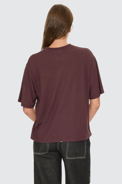 A full back view of the aubergine t-shirt on a model, demonstrating the clean, straight-cut paneling and smooth line across the upper back and shoulders.