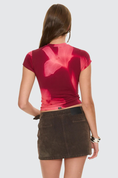 A full back view of the garnet orchid t-shirt on a model, highlighting the continuous and uniform flow of the hazy graphic yardage print across the shoulders down to the lower back.