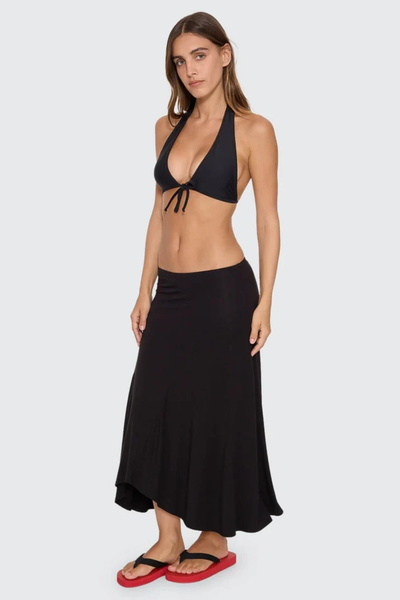 Full-length front view of model wearing the black Thrills Sienna Midi Skirt styled as resortwear with a black halter bikini top and red platform thongs.