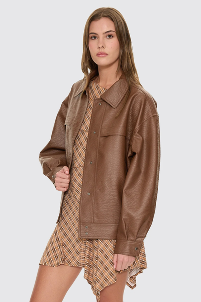 A full back view of the brown Stevie jacket on a model, showcasing the clean panel lines across the yoke and spine that highlight the matte sheen of the PU leather fabric.