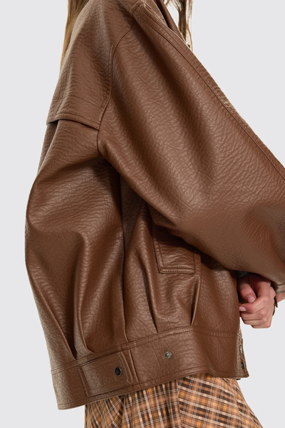 A detailed close-up shot focusing on the premium brown faux leather texture, highlighting the realistic grain pattern, subtle matte finish, and precise tonal topstitching.