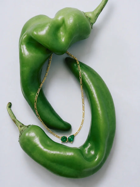 Macro detail shot of the emerald twin flame pendant positioned near the corner of a model's eye.