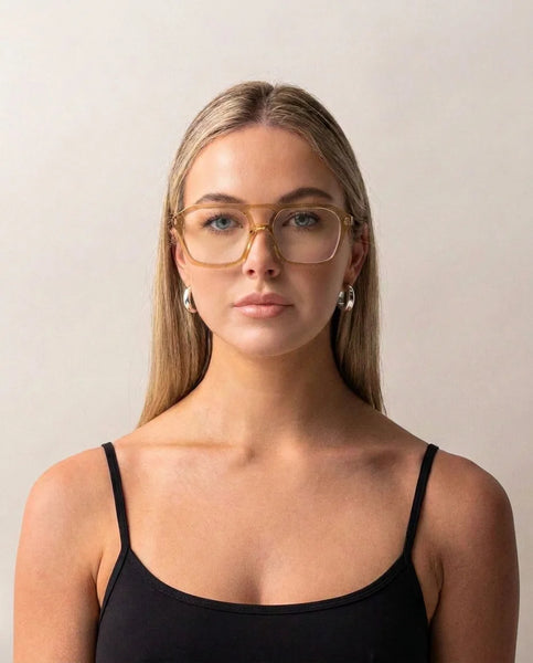 Headshot of a blonde woman facing forward wearing Sito Shades The Void Blue Light glasses in Sunlight with translucent aviator frames and clear lenses.