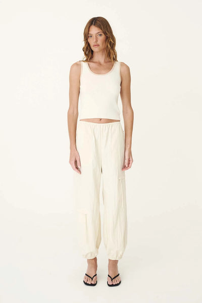 Full-length studio shot of a model wearing the ROWIE Blake Contrast Knit Tank in Oat Milk paired with cream Trist Balloon Pants and black sandals against a plain background.