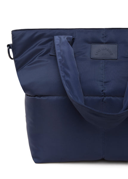 Shop the Barre multi-tasking tote in sophisticated navy. Featuring a fully insulated interior, internal pockets, and adjustable shoulder strap, this sleek recycled polyester bag is perfect for Pilates or daily errands.