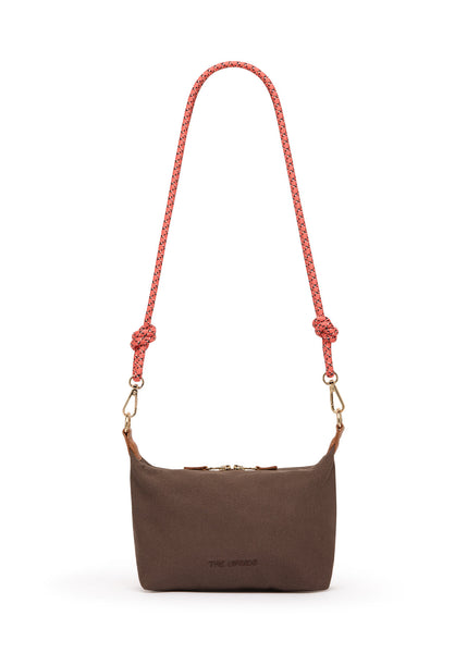 Flat studio image of The Upside Poppy Crossbody Bag in Chocolate, highlighting the chocolate brown cotton twill body, tonal front embroidered logo, gold hardware, tan leather trims, and coral pink paracord strap.