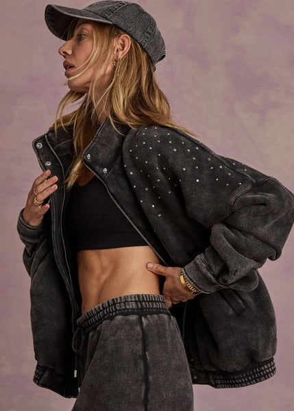 A zip-through moto-style jacket in washed black organic cotton fleece, featuring a high neck and silver rhinestone detailing on the shoulders.