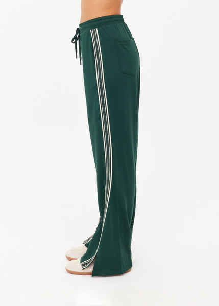 The Upside Roma Pant in racing green with vertical cream and green side-tape detailing and functional side seam pockets.