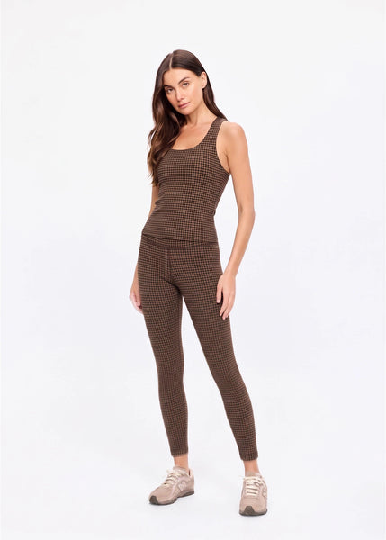 Full-length studio front view of a model standing straight, wearing the matching geo check tank top and leggings set with sneakers.