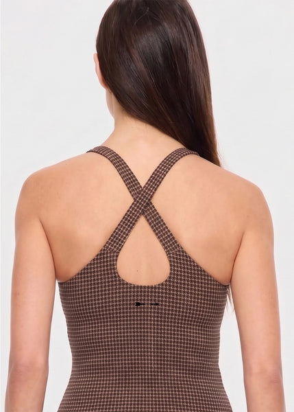 Close-up rear view of a model wearing the geo check tank top in tan, black, and brown, highlighting the cross-back straps and small printed arrow logo.