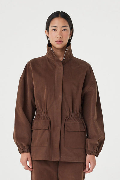 A detailed close-up shot focusing on the upper bodice of the Amari Jacket, cleanly highlighting the soft velvet texture of the 100% cotton fabric, the high funnel neck, and the concealed placket.