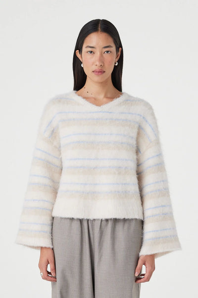 A detailed, upper-body studio close-up of the model facing forward. This shot prioritizes the tactile surface details of the recycled polyester-wool blend fabrication, detailing the fuzzy, fluffy knit fiber texture and the clean line of the relaxed V-neck silhouette.
