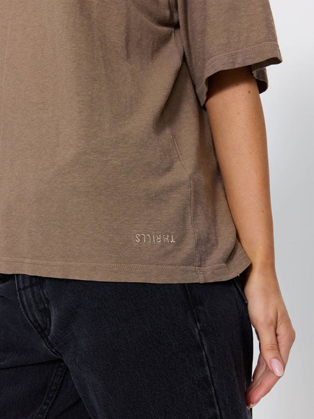 Close-up detail shot of the hemline on the Thrills Hemp Square Tee in Falcon brown, showing the tonal embroidered Thrills logo and textured hemp-cotton jersey weave.