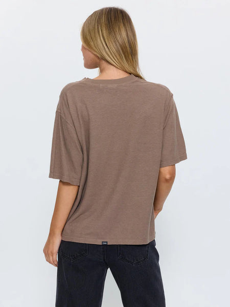 Rear view studio shot of a model wearing the Thrills Hemp Square Tee in Falcon brown paired with dark denim jeans, showcasing the roomy sleeves and straight back hem.