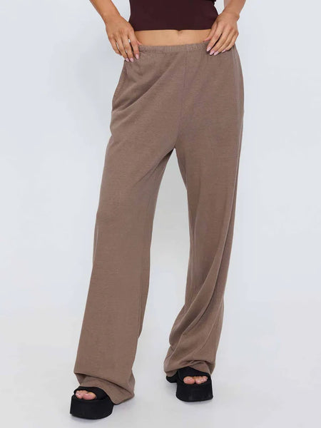 Full-length studio portrait of a model posing in the Thrills Hemp Relax Pant in Falcon brown, styled with a dark brown cropped tank top and black platform sandals.