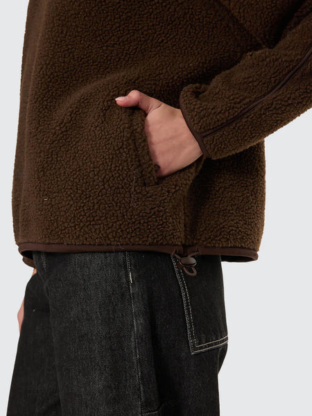A dynamic full-length winter shot of a model walking, demonstrating the comfortable movement, cold-weather layering depth, and premium cozy appeal of the heavyweight streetwear piece.