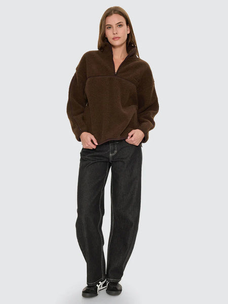 A shot focusing on the high-neck collar of the brown fleece, showcasing the quarter-zip tracking fully zipped up, the plush pile of the 100% polyester fabric, and the protective black binding trim.
