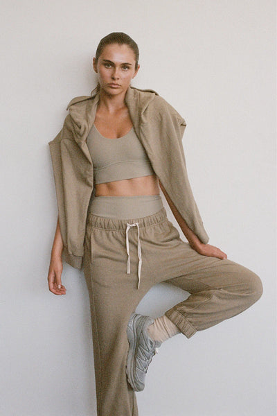 A full-length studio product shot displaying the olive cuffed fleece sweatpants paired with a matching neutral crop top, highlighting the gathered elastic waistband and the contrast off-white adjustable tie drawcord.