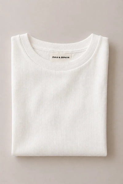 Flat lay view of the Zulu & Zephyr Rib Hemp Jersey Long Sleeve Top in white neatly folded, highlighting the bound crew neckline and woven brand tag.