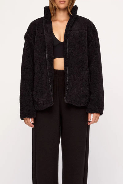Mid-shot of a model wearing the black zip-up Zulu & Zephyr Sherpa Jacket with a high collar, showing the textured plush recycled sherpa finish and relaxed drop-shoulder silhouette.