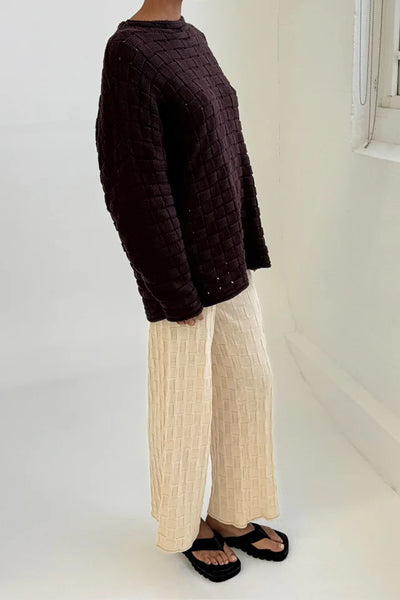 A side profile view from the shoulder down, accentuating the loose-cut armholes, easy-layering sleeve width, and the thick, premium hand feel of the heavy yarn.