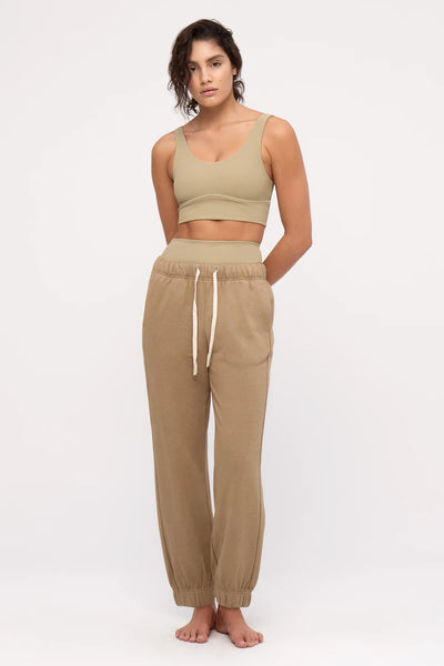 A full-length studio product shot displaying the olive cuffed fleece sweatpants paired with a matching neutral crop top, highlighting the gathered elastic waistband and the contrast off-white adjustable tie drawcord.