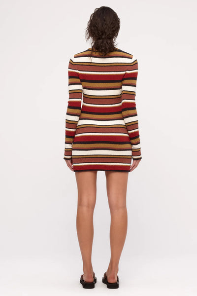 The Earth Stripe knit dress styled as a statement piece, highlighting its ability to be worn alone or layered over pants for an elevated look.