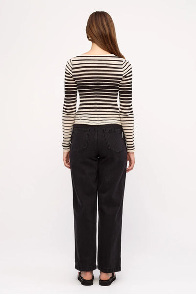 Rear view studio portrait of a model wearing the Zulu & Zephyr Ramie Cotton Knit Top in Ombre Stripe paired with high-waisted black straight-leg jeans.