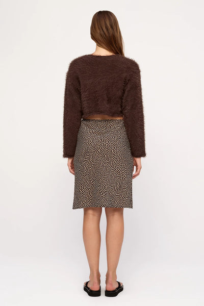 Rear studio view of a model wearing the cropped Zulu & Zephyr Fully Knit Cardigan in Chocolate made from soft fluffy fabric, styled with a patterned brown midi skirt.